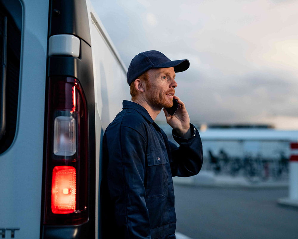 Man talking on phone next to LCV at sunset