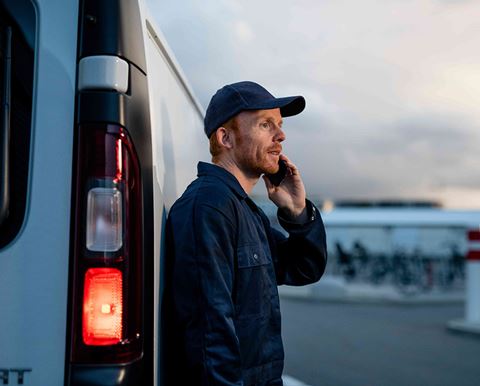 Man talking on phone next to LCV at sunset